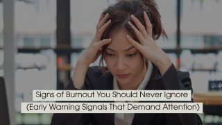 Person sitting at a desk holding their head with both hands, appearing stressed and overwhelmed, symbolizing burnout and mental fatigue, with the text “Signs of Burnout You Should Never Ignore (Early Warning Signals That Demand Attention)” displayed across the image.