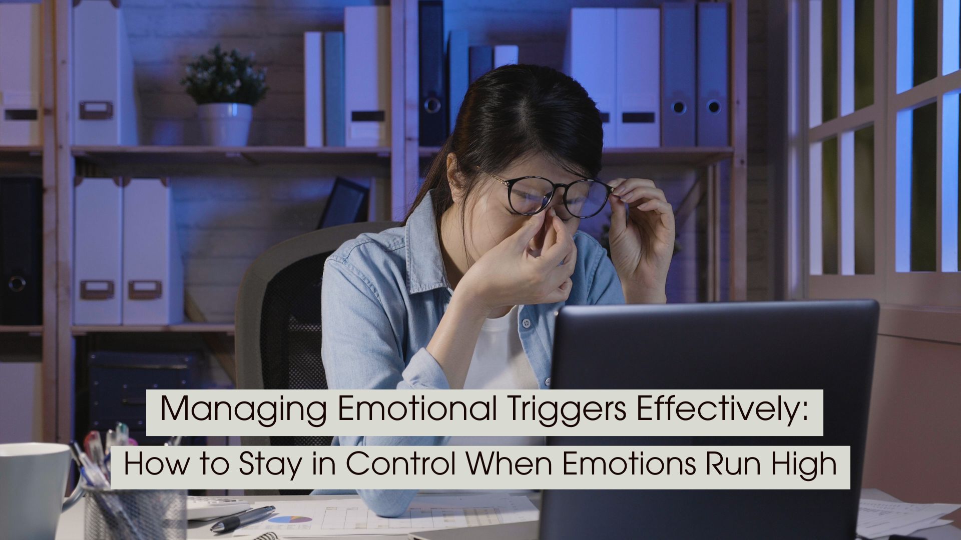 A tired woman working late at a desk rubs the bridge of her nose while sitting in front of a laptop, illustrating emotional overwhelm, stress, and trigger management in a high-pressure environment, with the text “Managing Emotional Triggers Effectively: How to Stay in Control When Emotions Run High” displayed across the image.