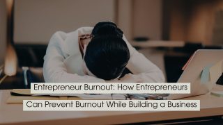 Exhausted entrepreneur resting their head on a desk beside a laptop and paperwork, with the text “Entrepreneur Burnout: How Entrepreneurs Can Prevent Burnout While Building a Business” displayed across the image.
