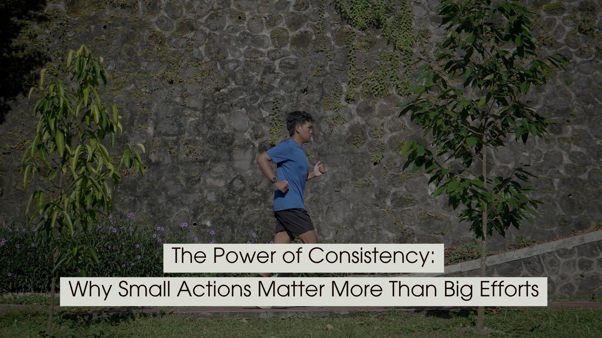 Person jogging outdoors along a path beside a stone wall and greenery, representing steady progress and daily consistency, with the text “The Power of Consistency: Why Small Actions Matter More Than Big Efforts” displayed across the image.