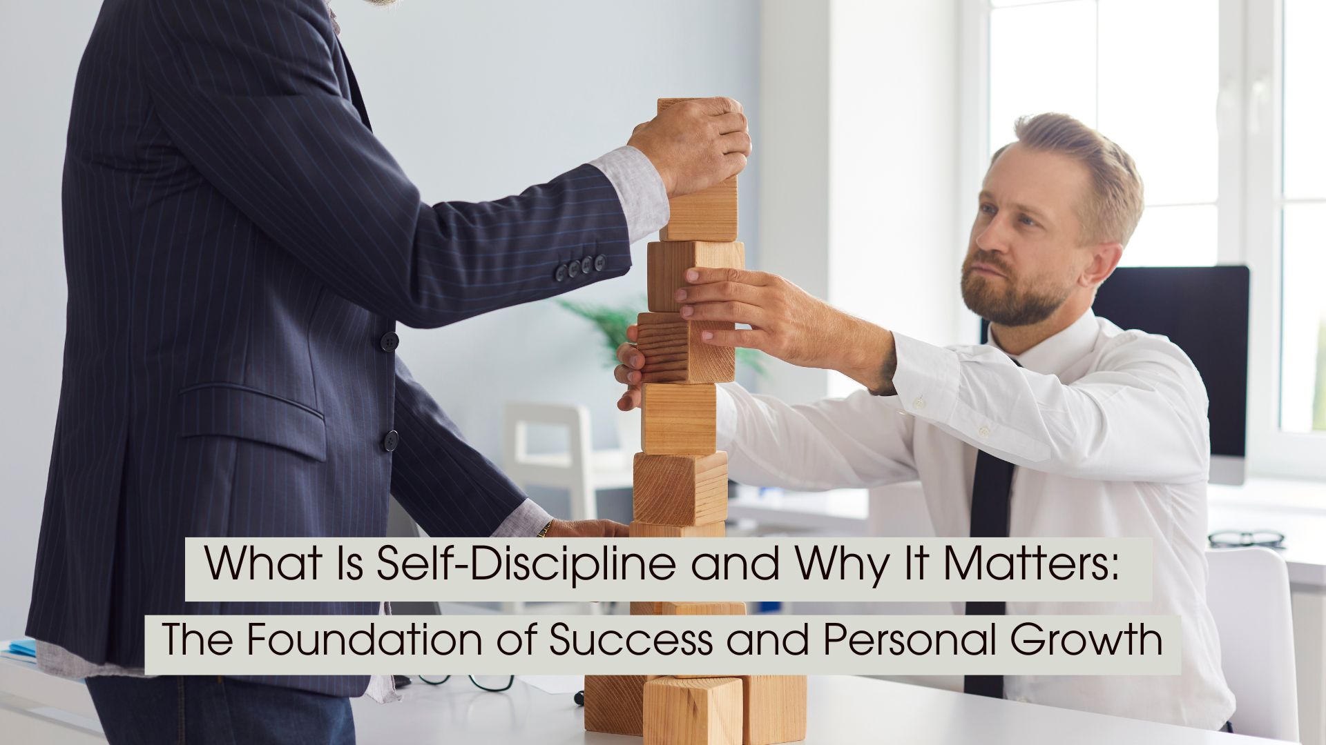 Two professionals work together to carefully balance wooden blocks in a Jenga-style tower, symbolizing the discipline, patience, consistency, and deliberate choices needed to build lasting success. The bright office setting reinforces the connection between self-discipline, personal growth, and professional achievement. Overlaid text reads: “What Is Self-Discipline and Why It Matters: The Foundation of Success and Personal Growth.”