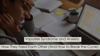 Stressed person sitting at a desk with head in hand beside an open laptop and scattered papers, representing imposter syndrome and anxiety.