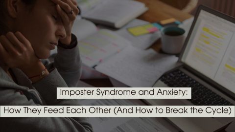 Stressed person sitting at a desk with head in hand beside an open laptop and scattered papers, representing imposter syndrome and anxiety.