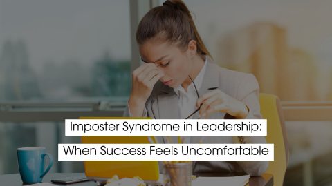 Female leader in a business setting holding her glasses and rubbing her forehead, illustrating imposter syndrome in leadership, self-doubt, work stress, and discomfort with professional success.