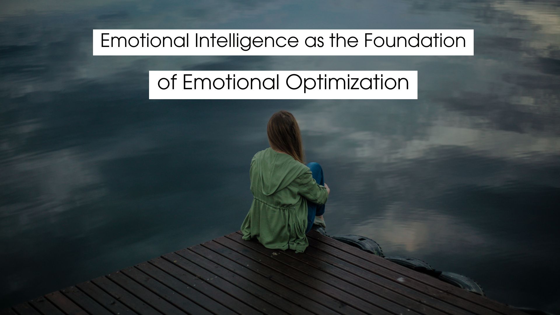 Person sitting quietly on a wooden dock overlooking calm water, reflecting on emotions and mindfulness, representing emotional intelligence as the foundation of emotional optimization.