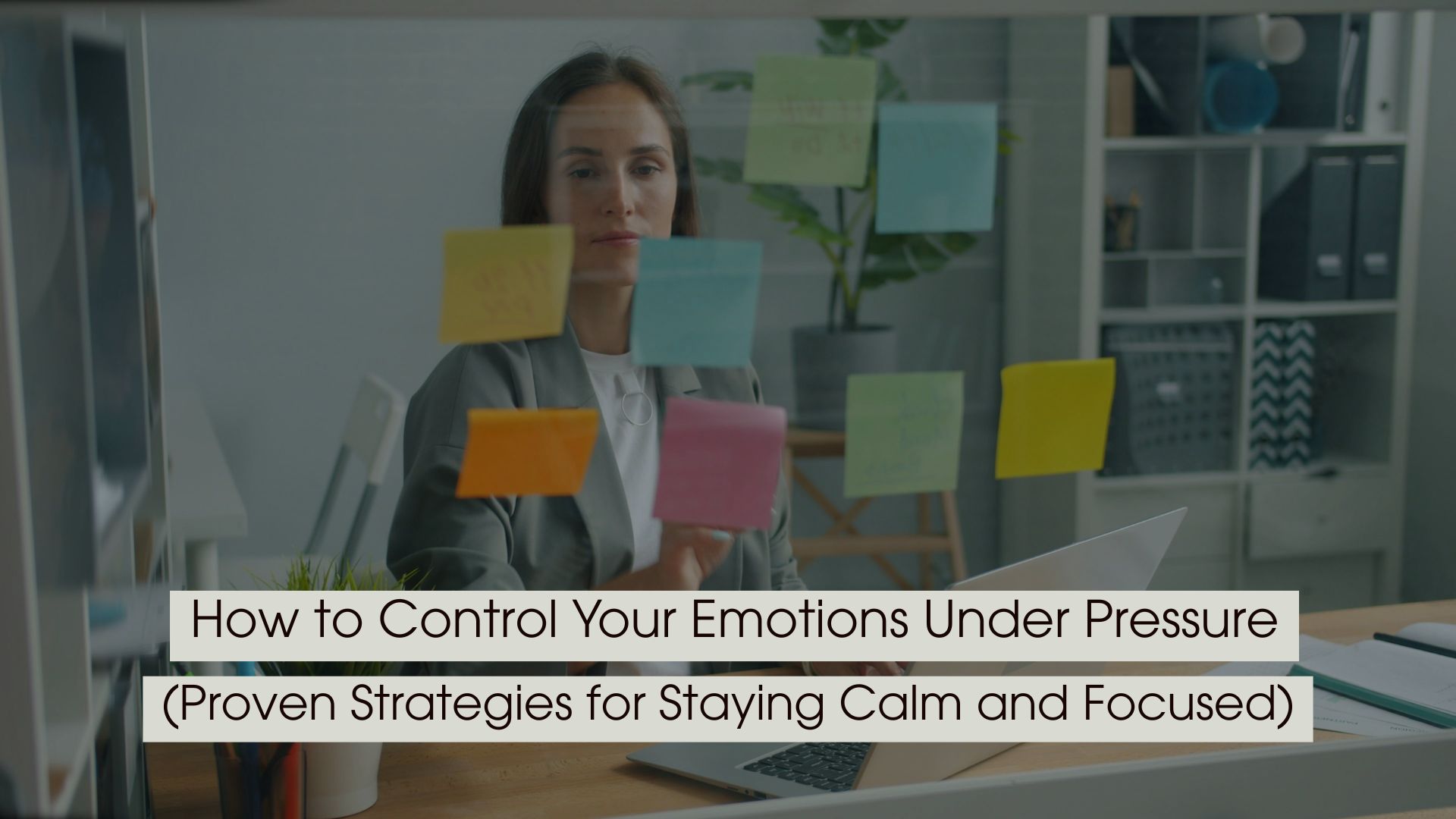 A woman in an office organizing colorful sticky notes on a glass board while working on a laptop, representing focus and emotional control under pressure, with the text “How to Control Your Emotions Under Pressure (Proven Strategies for Staying Calm and Focused)” displayed across the image.