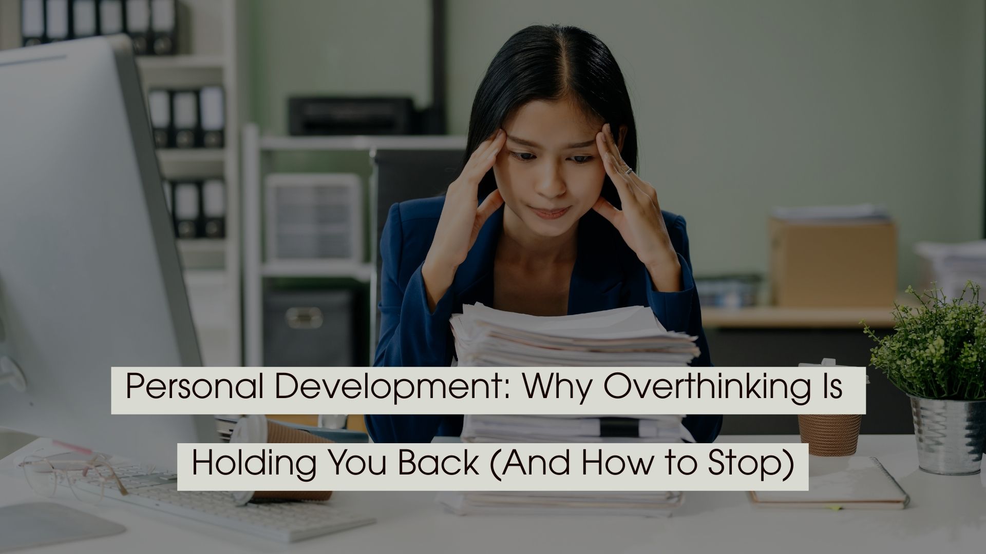 Woman in an office setting looking stressed while holding her temples and staring at a stack of papers, with the text “Personal Development: Why Overthinking Is Holding You Back (And How to Stop)” displayed across the image.